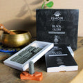Ishom Black Oudh incense bricks with packaging on a wooden surface.
