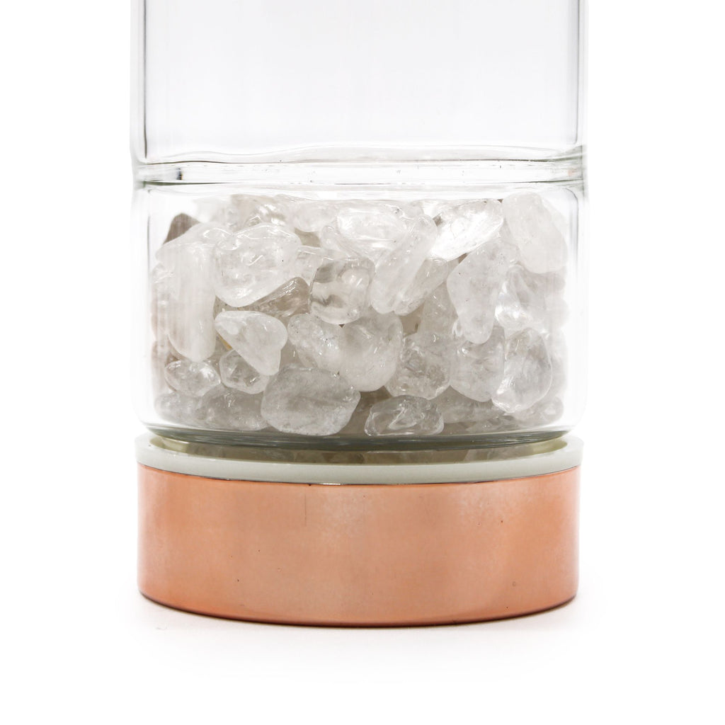 Clear glass container with copper base filled with ice cubes on a white background