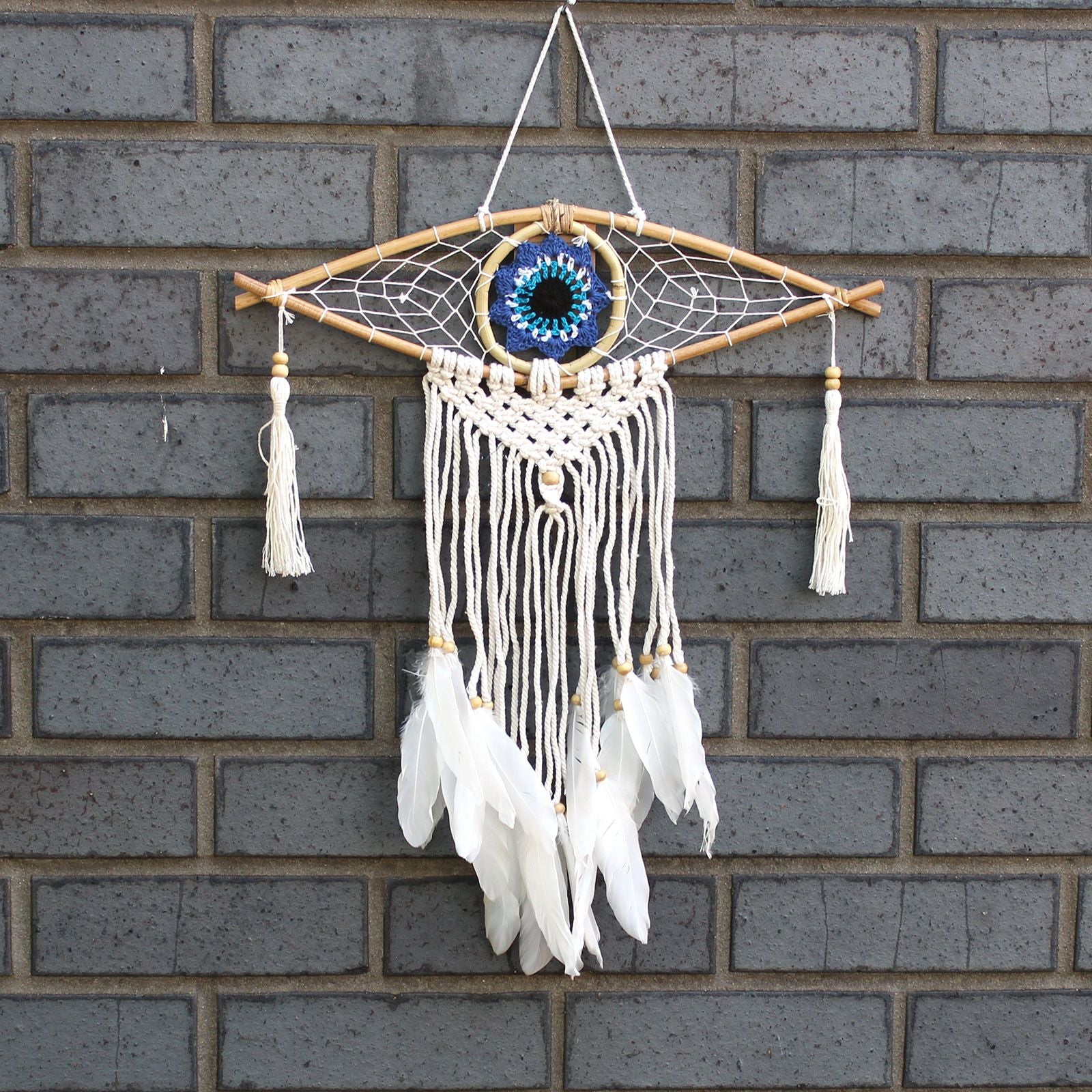Dreamcatcher with feathers hanging on a brick wall