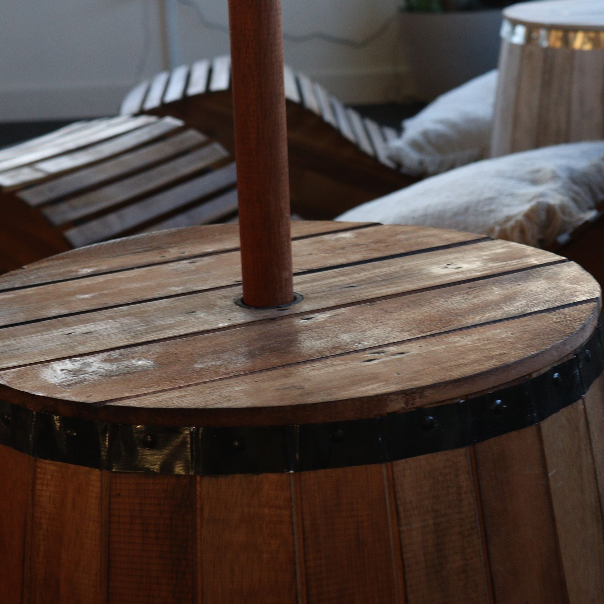 Wooden barrel with a metal band and umbrella stand in an outdoor setting