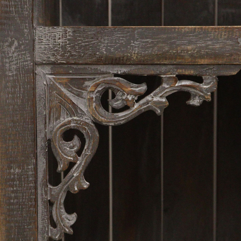 Decorative metal bracket on a wooden surface with a dark background