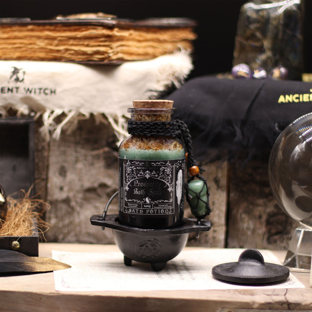 Black bottle with label on a wooden surface with witchcraft-themed decor.