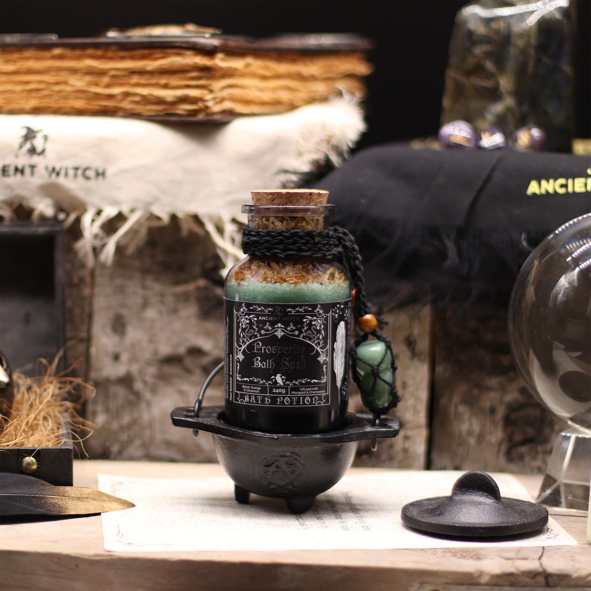 Black bottle with label on a wooden surface with witchcraft-themed decor.