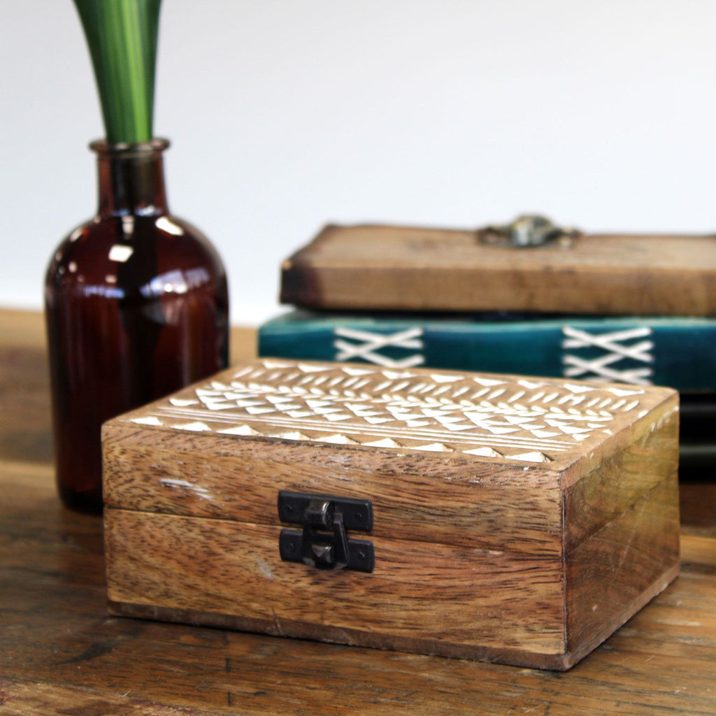 Wooden box with geometric patterns on a wooden surface with a blurred background
