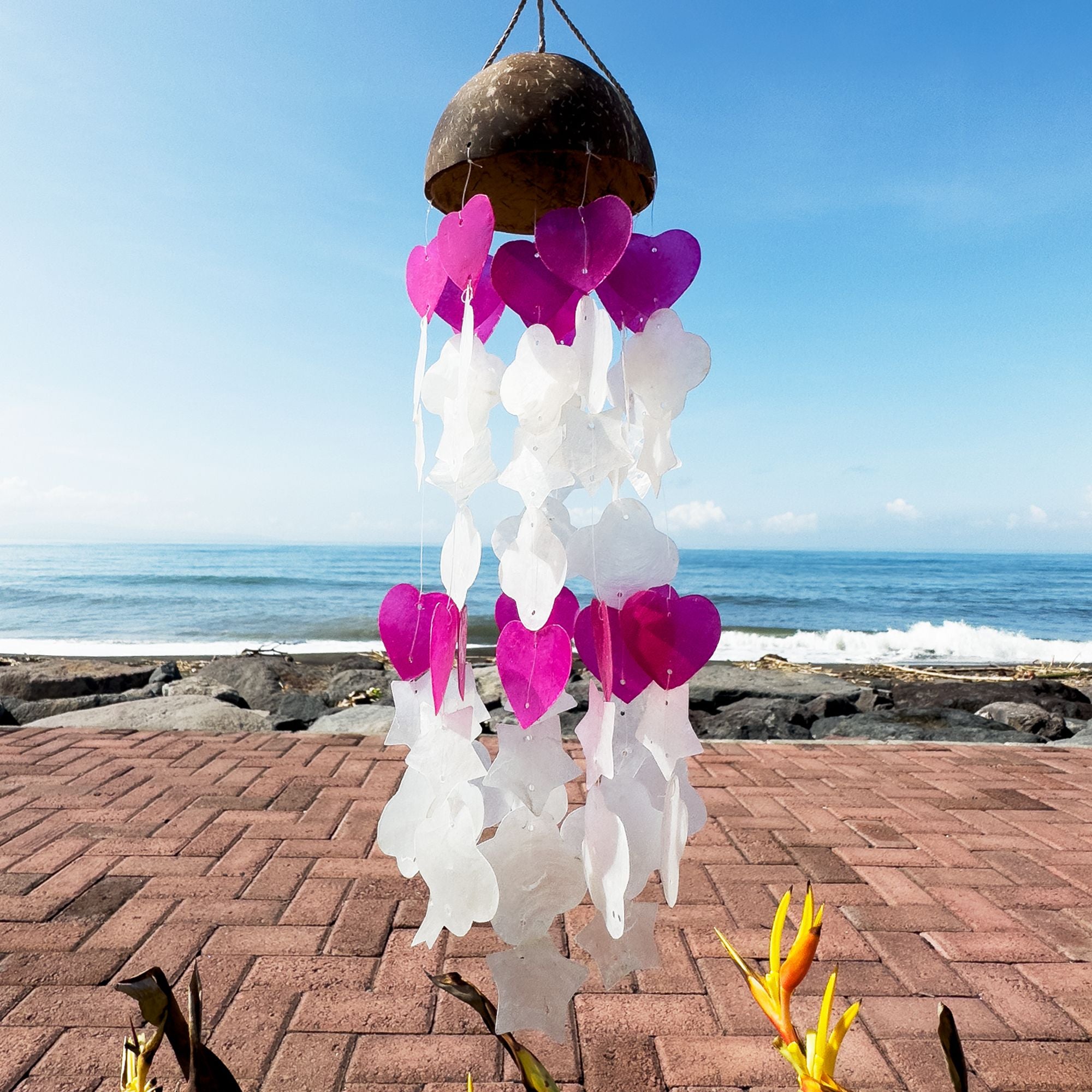 Decorative wind chime with pink hearts on a beach