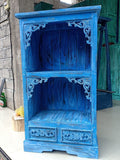 Blue ornate wooden cabinet against a stone wall.