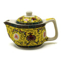 Yellow ceramic teapot with intricate designs on a white background