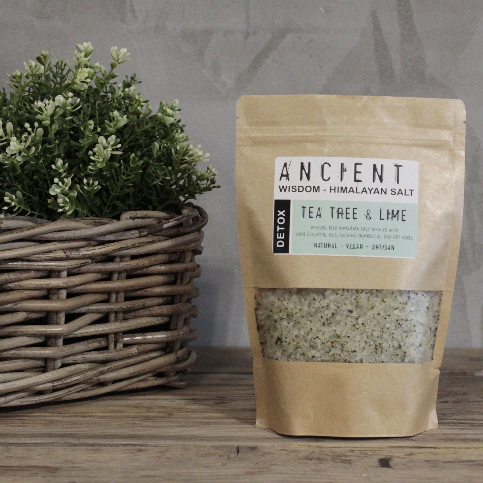 Bag of tea tree and lime Himalayan salt on a wooden surface with a plant in the background