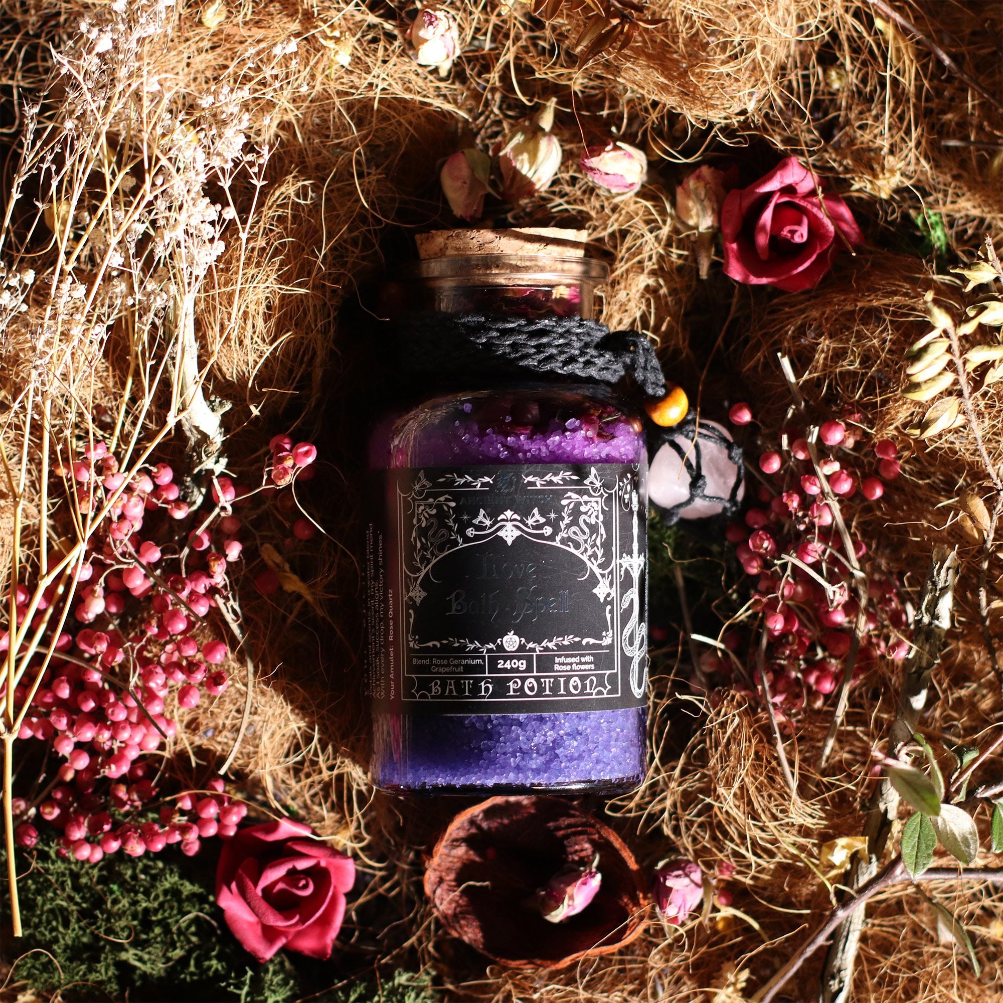 Purple potion bottle with decorative label surrounded by flowers and herbs on straw