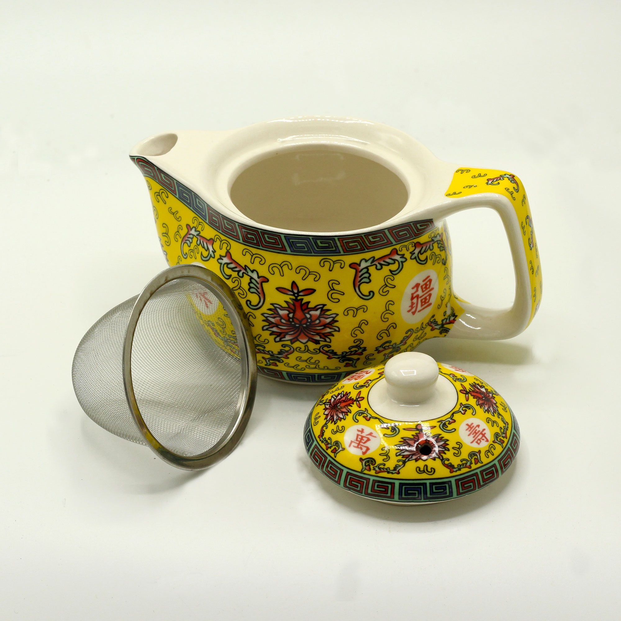 Yellow ceramic teapot with floral patterns on a white background
