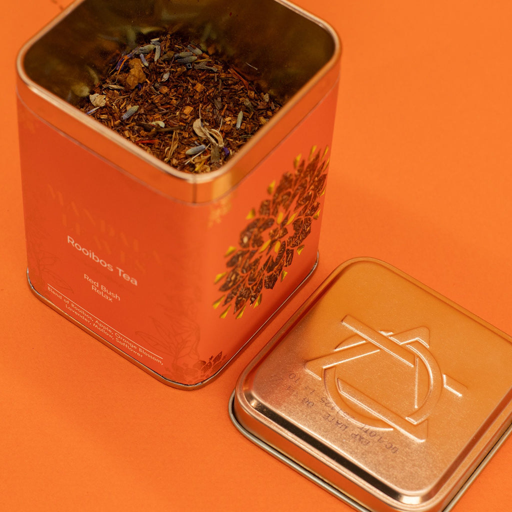 Open orange tea tin with branding on an orange background