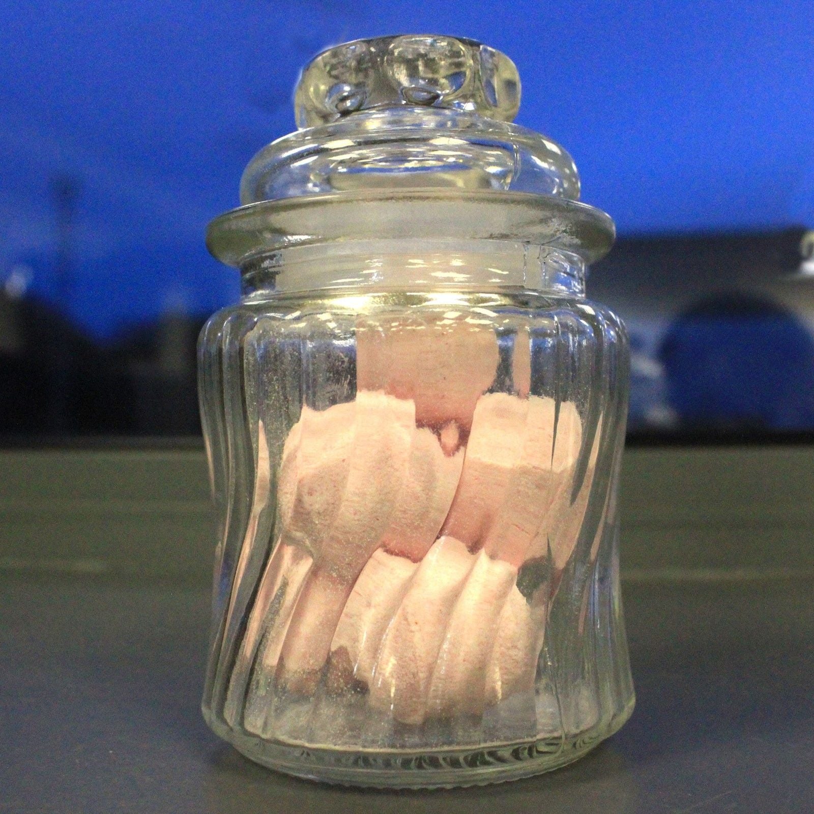 Clear glass jar with pink cotton swabs against a blue background