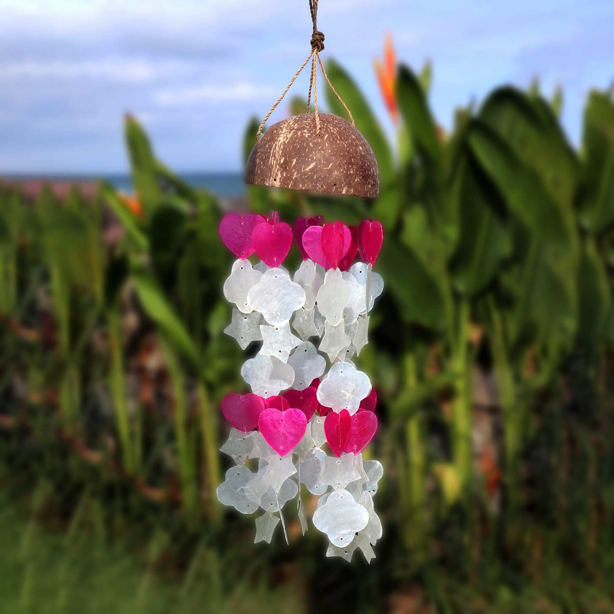 Decorative hanging mobile with pink and white heart shapes against a blurred natural background