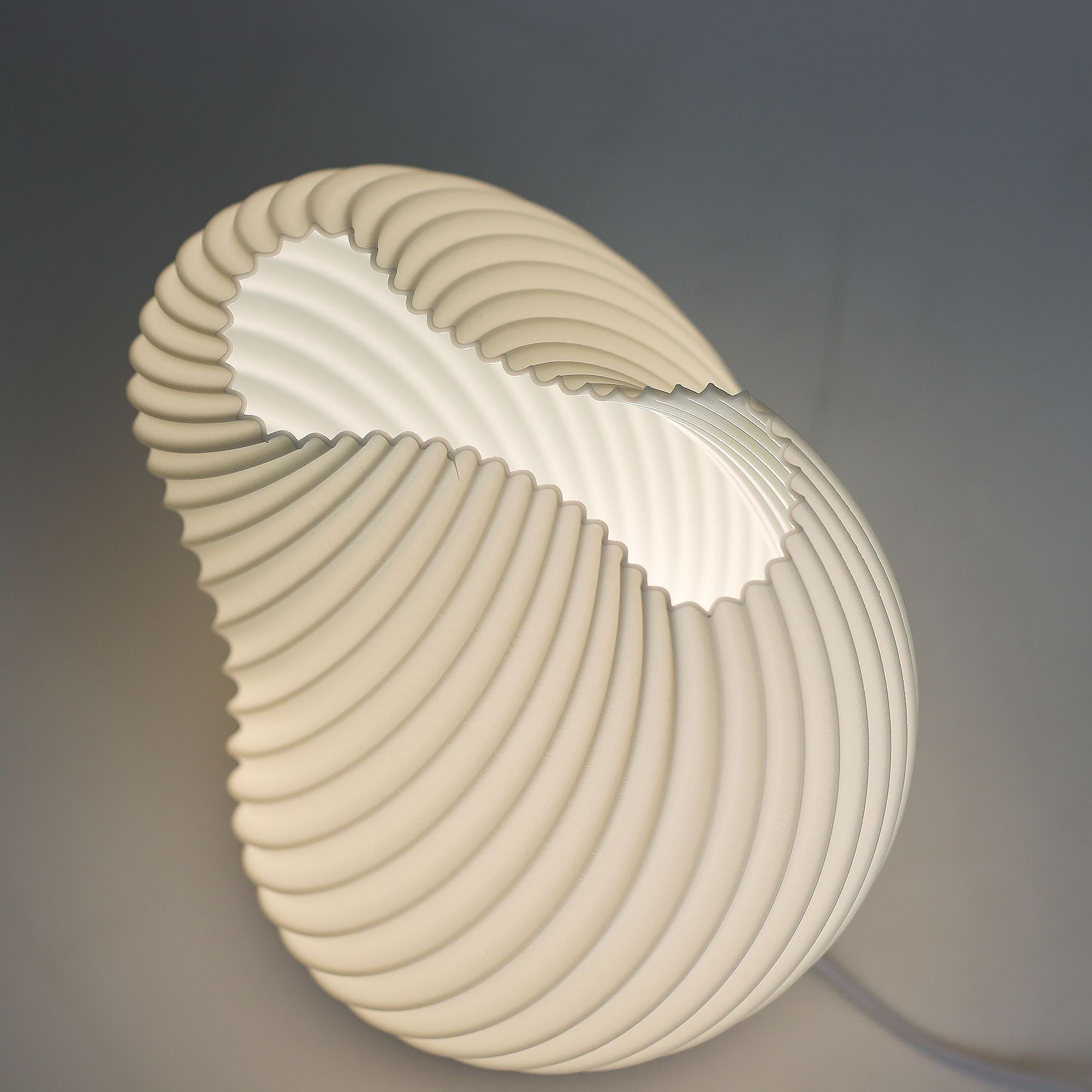 Modern wall light fixture with a shell-like design on a dark background