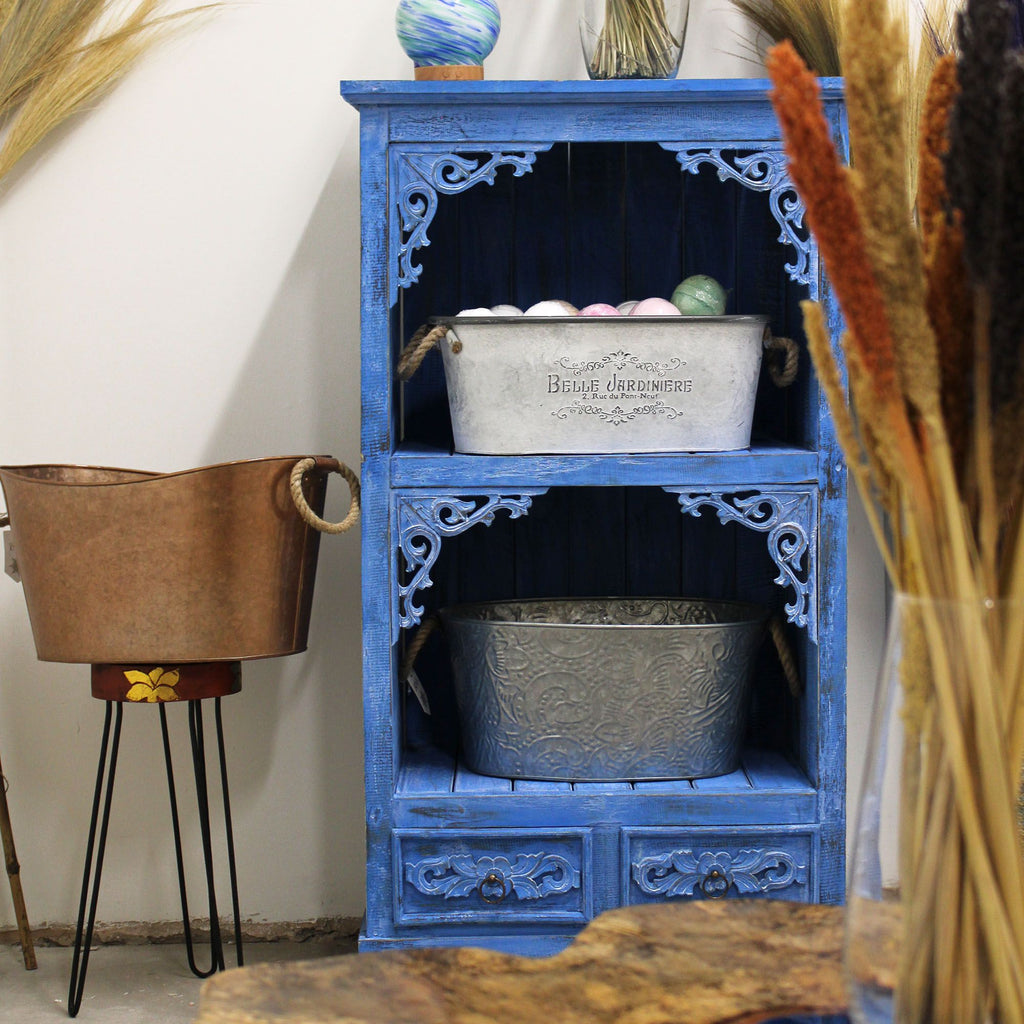 Blue decorative cabinet with metal buckets and a white wall background