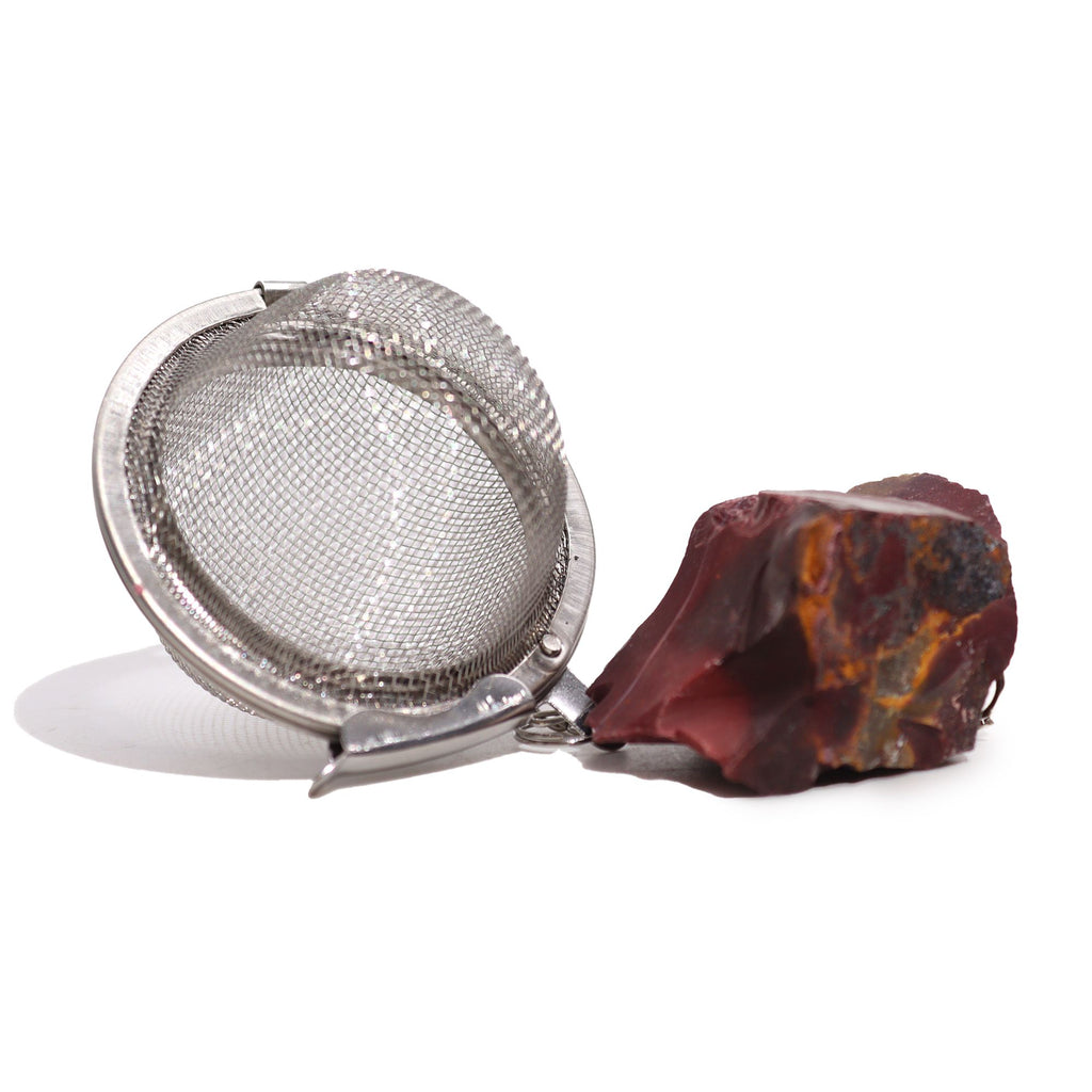 Metallic tea infuser with a red stone on a white background