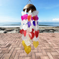 Colorful heart-shaped wind chime on a brick patio with ocean view