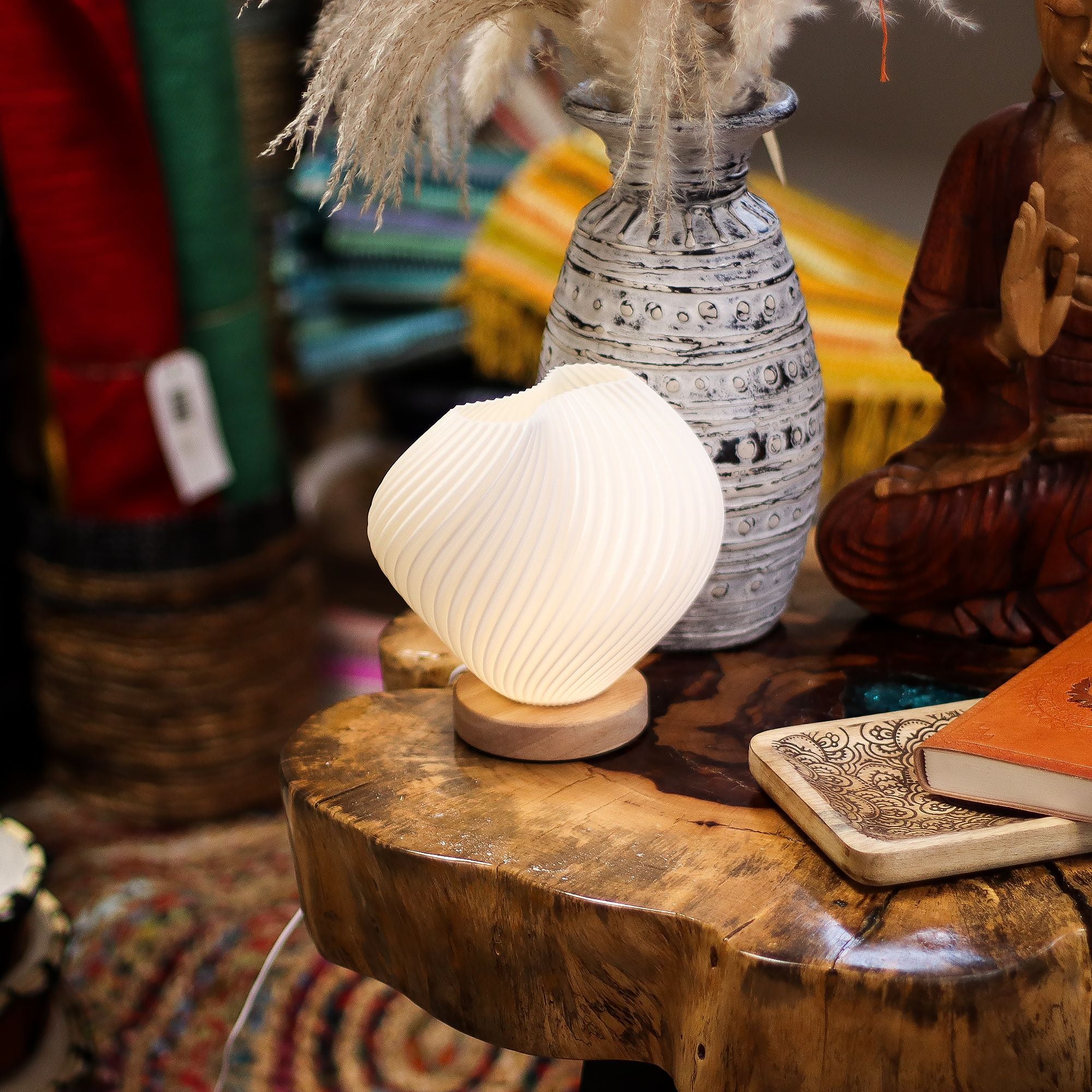 Decorative lamp on a wooden surface with a vase and statue in the background
