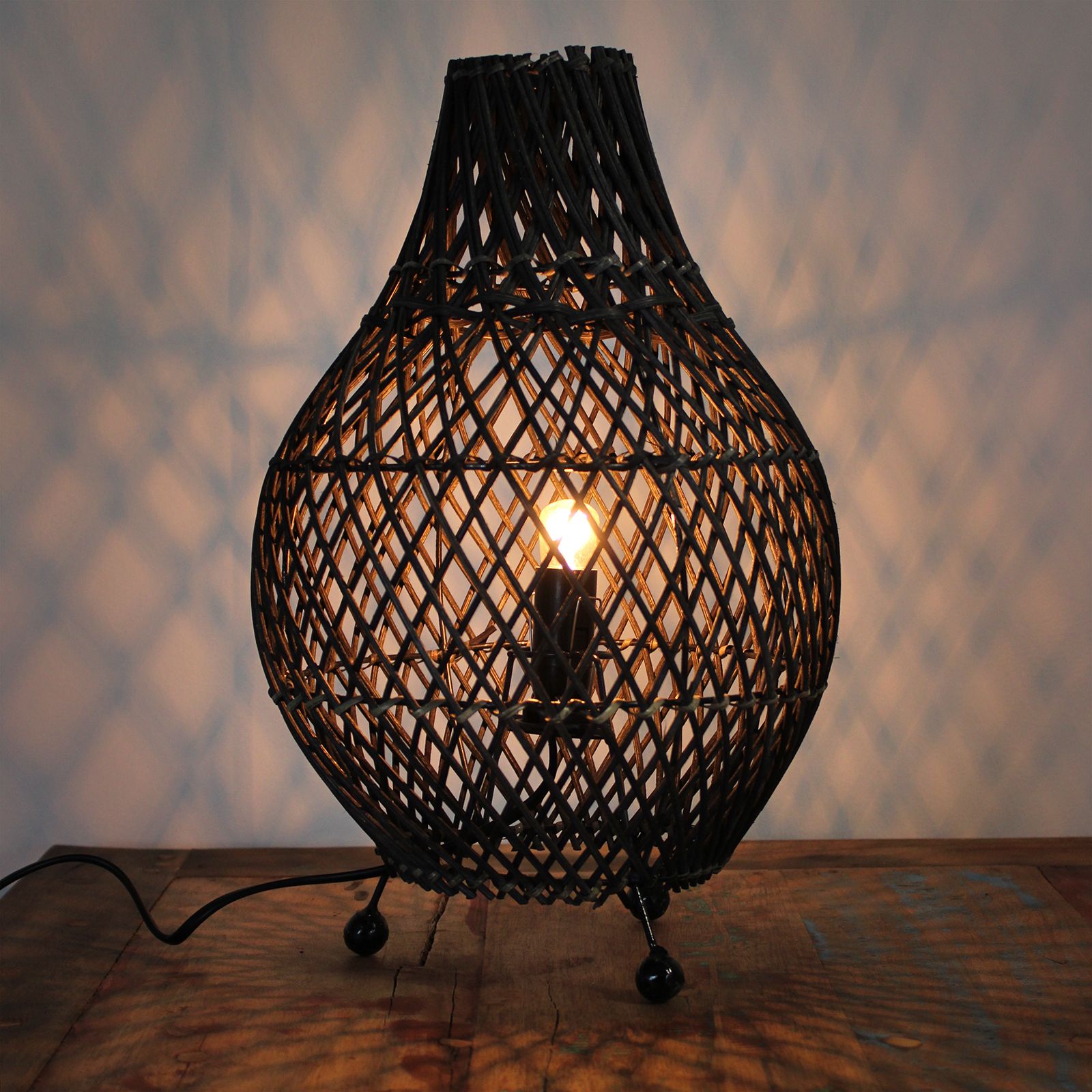 Woven lamp with a warm glow on a wooden surface
