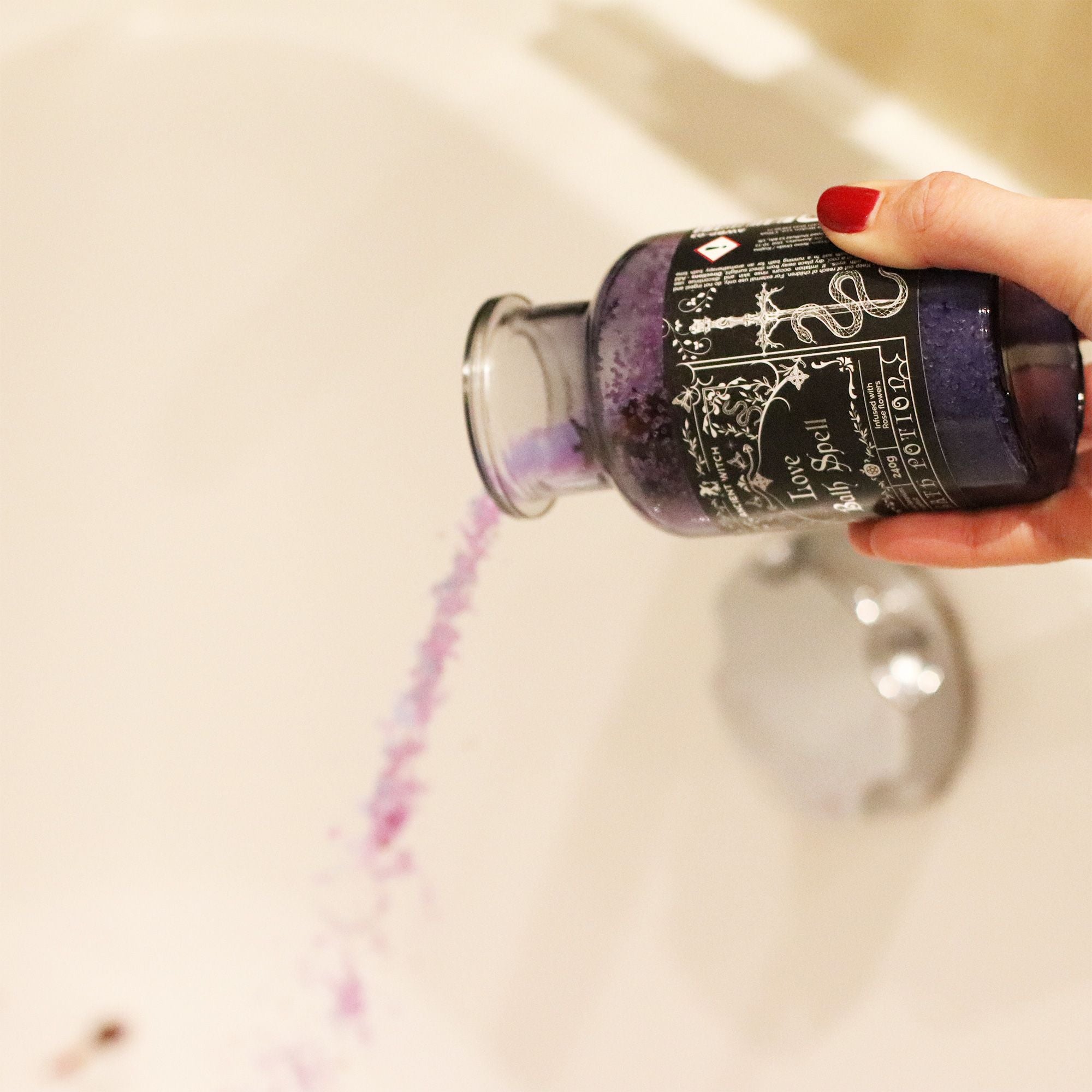 Hand holding a bottle of purple ink with a decorative label against a neutral background