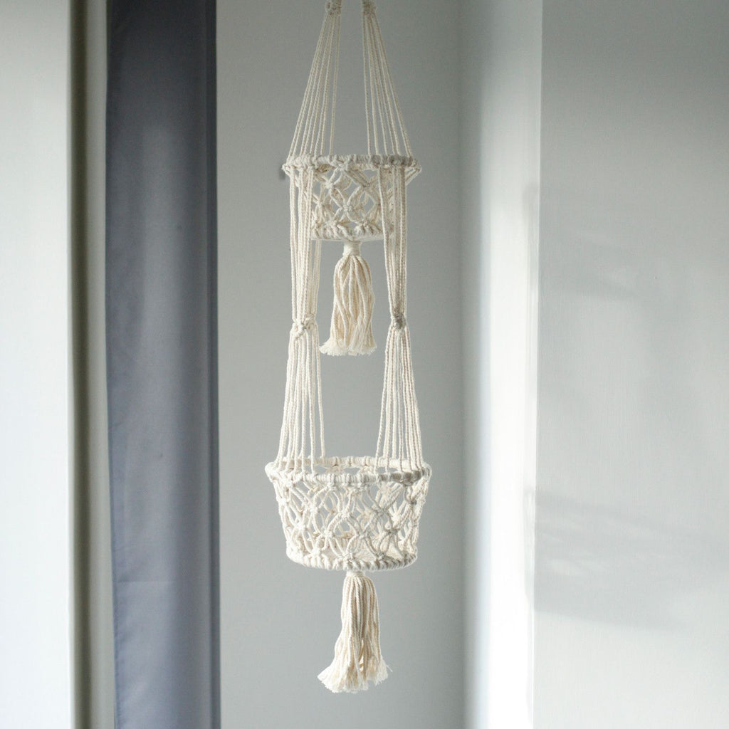 Macrame plant hanger with tassels on a gray background
