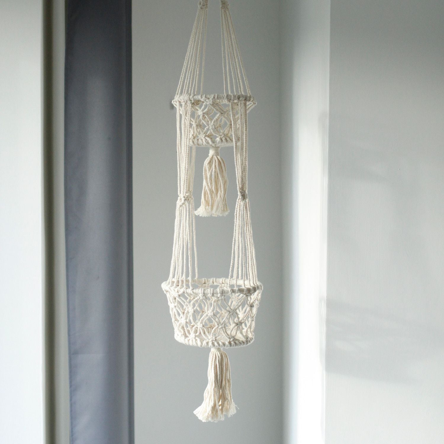 Macrame plant hanger with tassels on a gray background