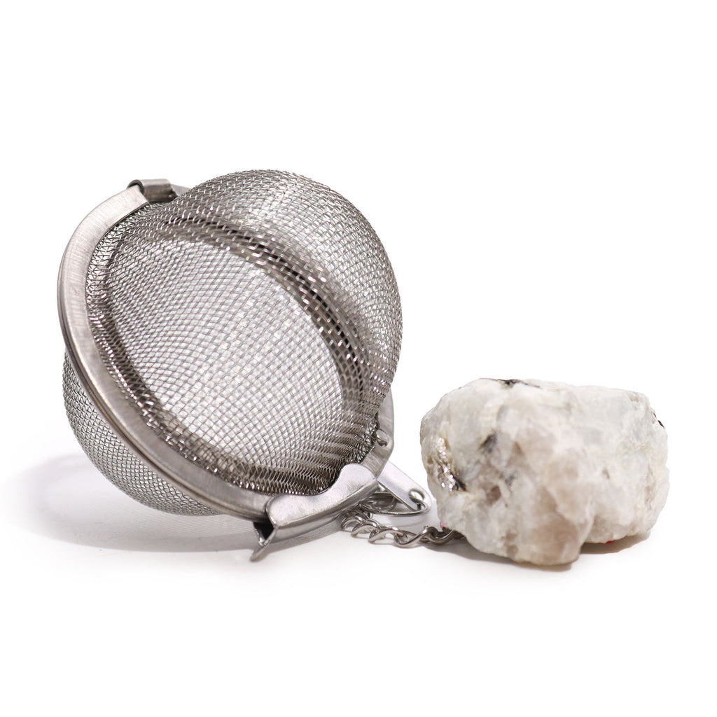 Metallic tea ball infuser with a stone on a white background