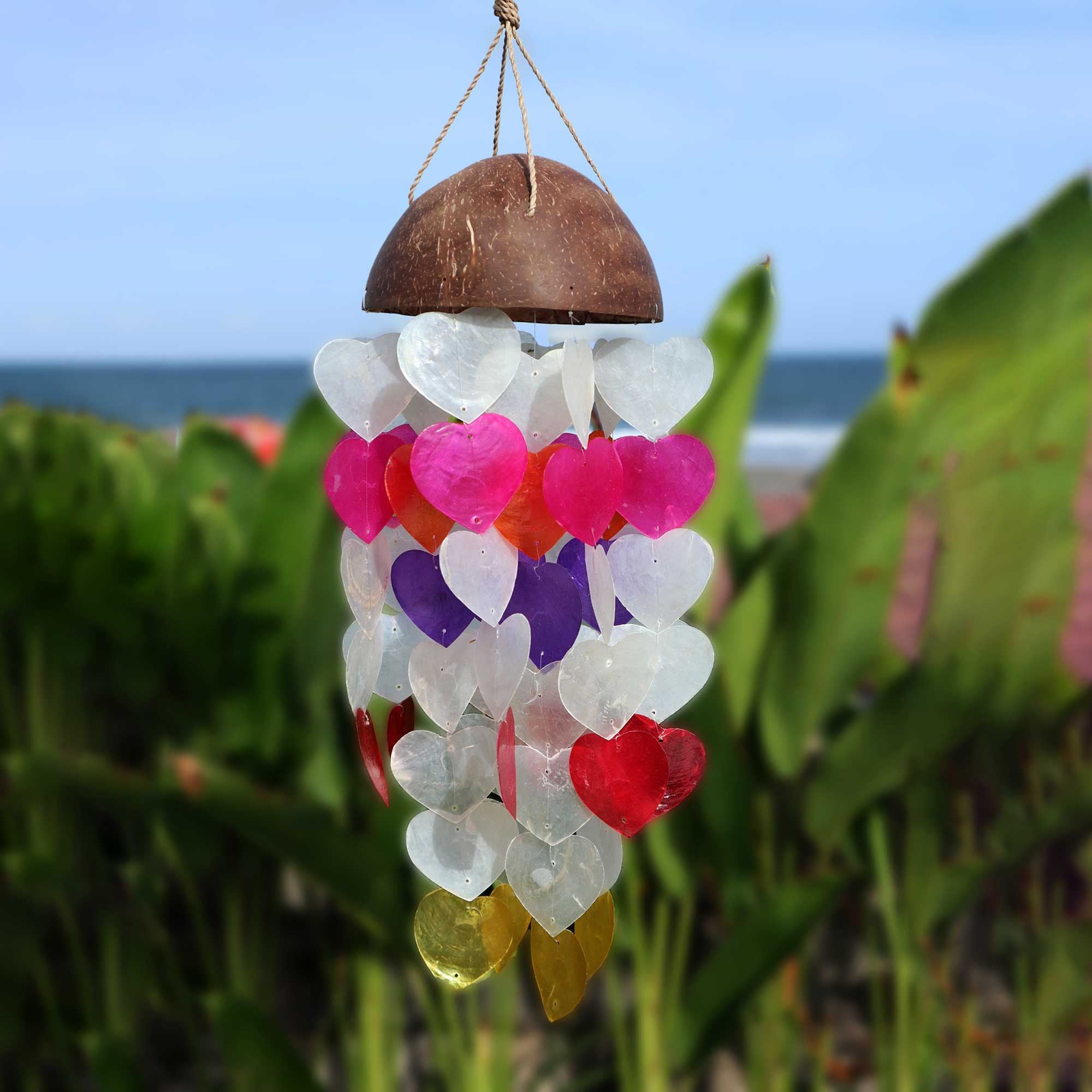 Colorful heart-shaped seaglass wind chime hanging against a beach backdrop