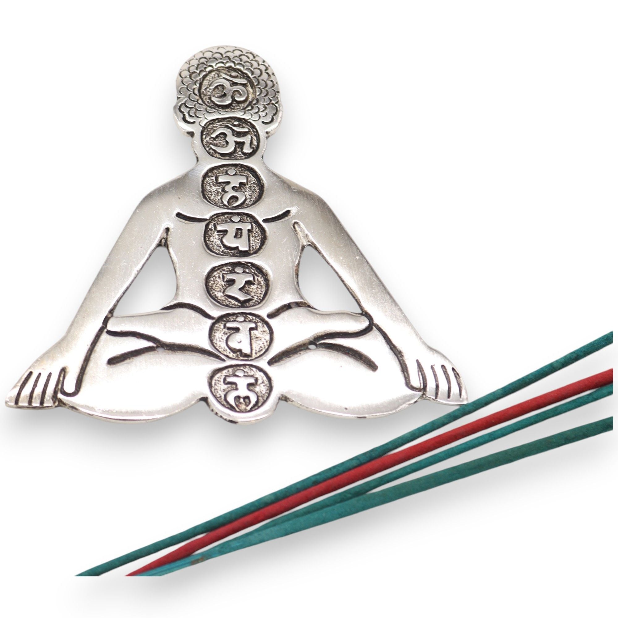 Silver figure of a person in a meditative pose with engraved symbols, placed on a white background.
