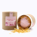 Pink bath bomb in a cardboard container with a pink label on a white background