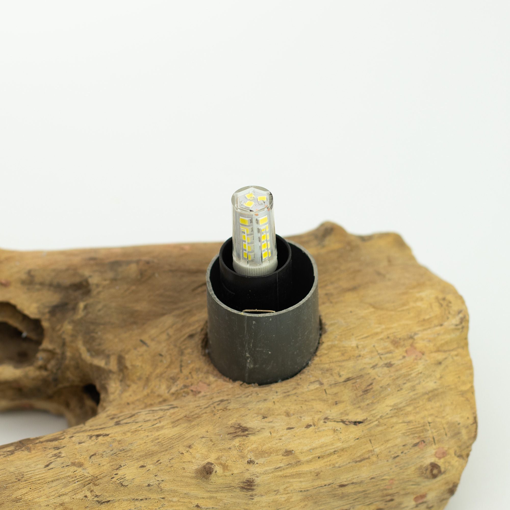 LED light bulb in a holder on a piece of wood with a white background