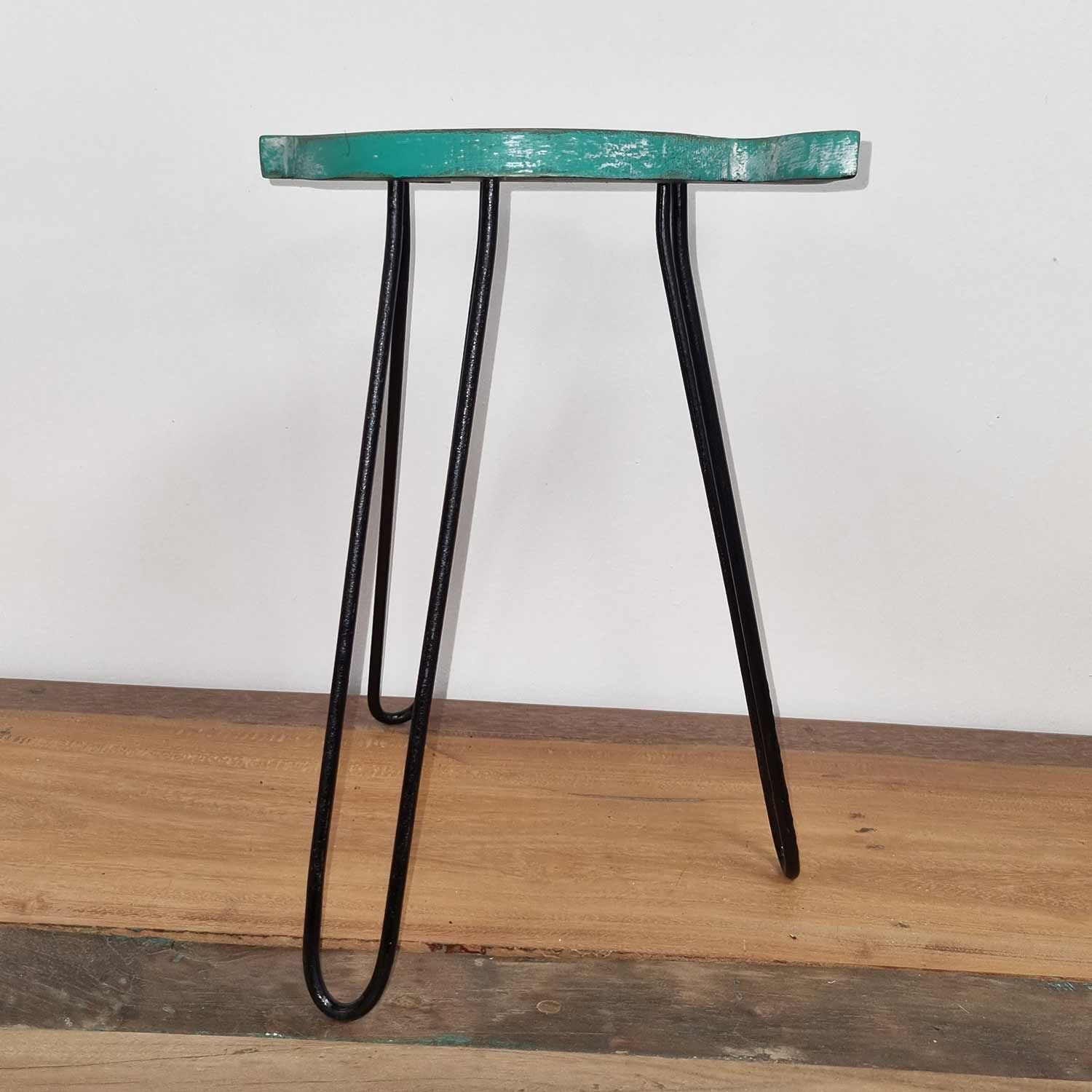 Small stool with a teal seat and black metal legs on a wooden floor.