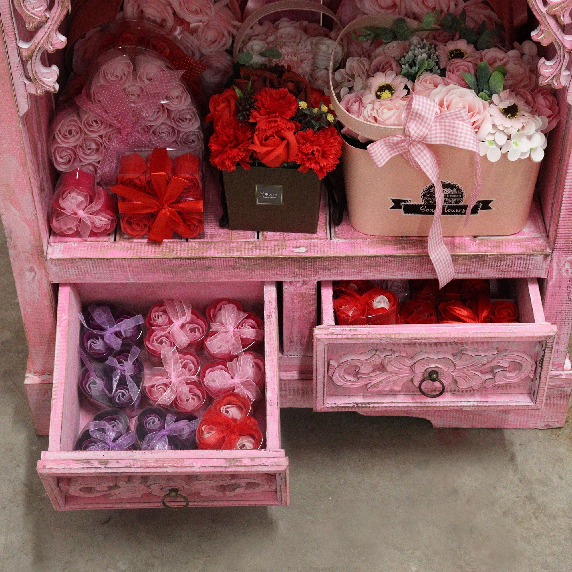 Pink decorative cabinet with flowers, gift boxes, and ribbons.
