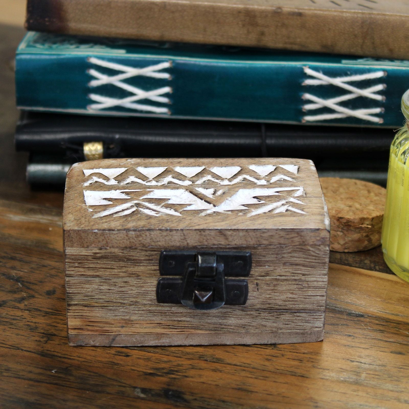 Wooden box with geometric patterns on a wooden surface with books in the background
