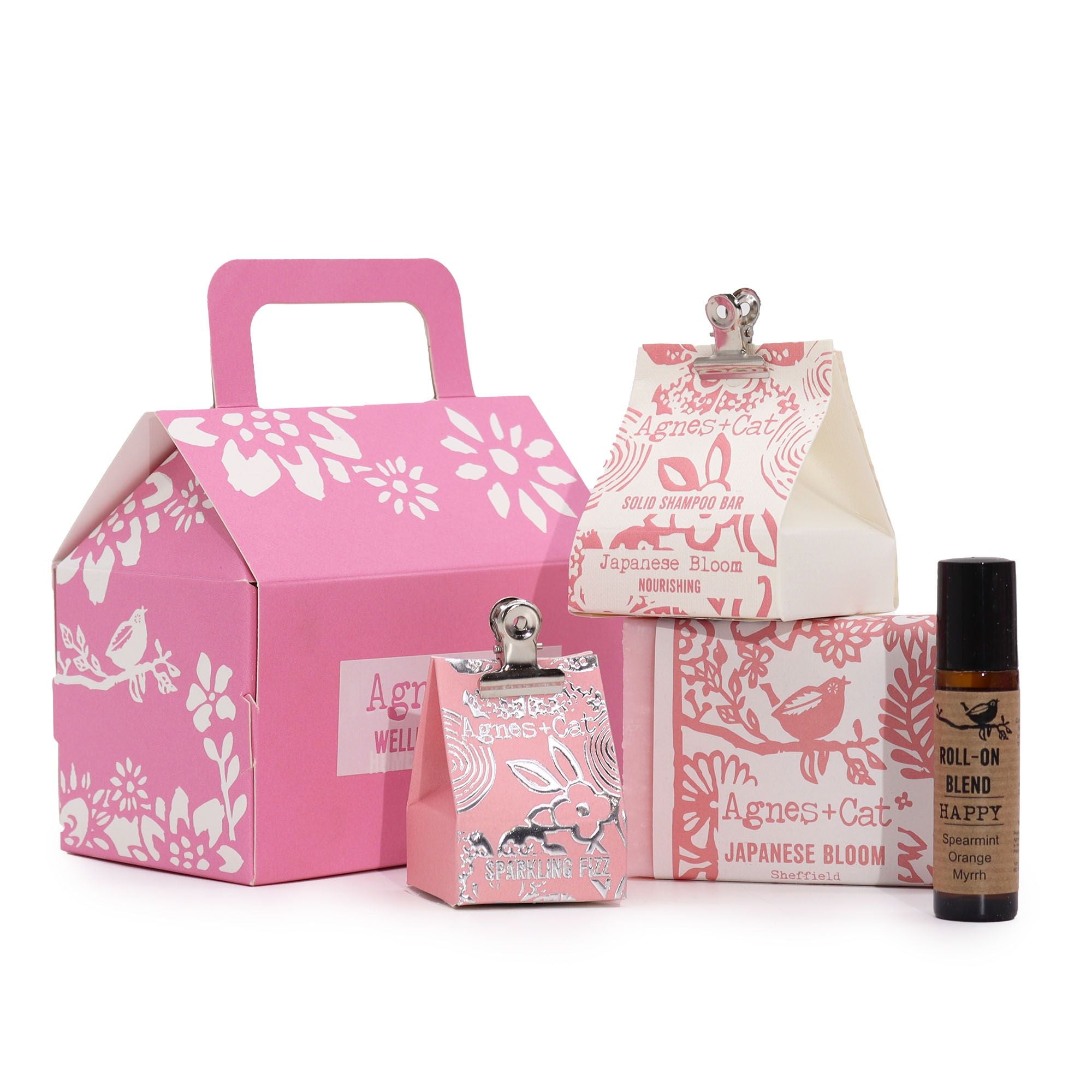 Collection of Agnes & Cat products including a pink box, small bottles, and a rollerball on a white background.