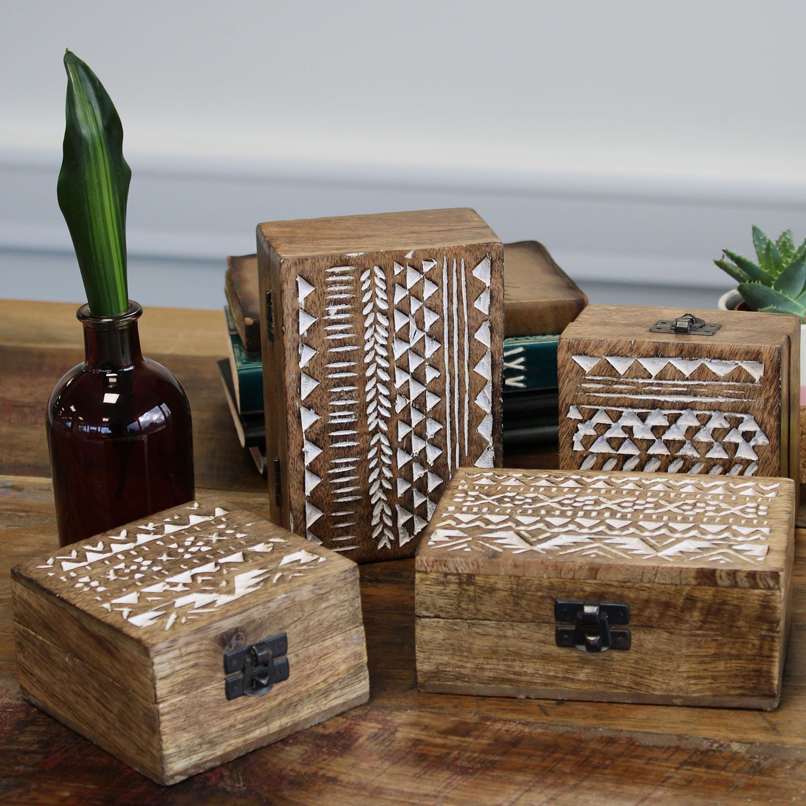 Set of wooden boxes with geometric patterns on a wooden surface.