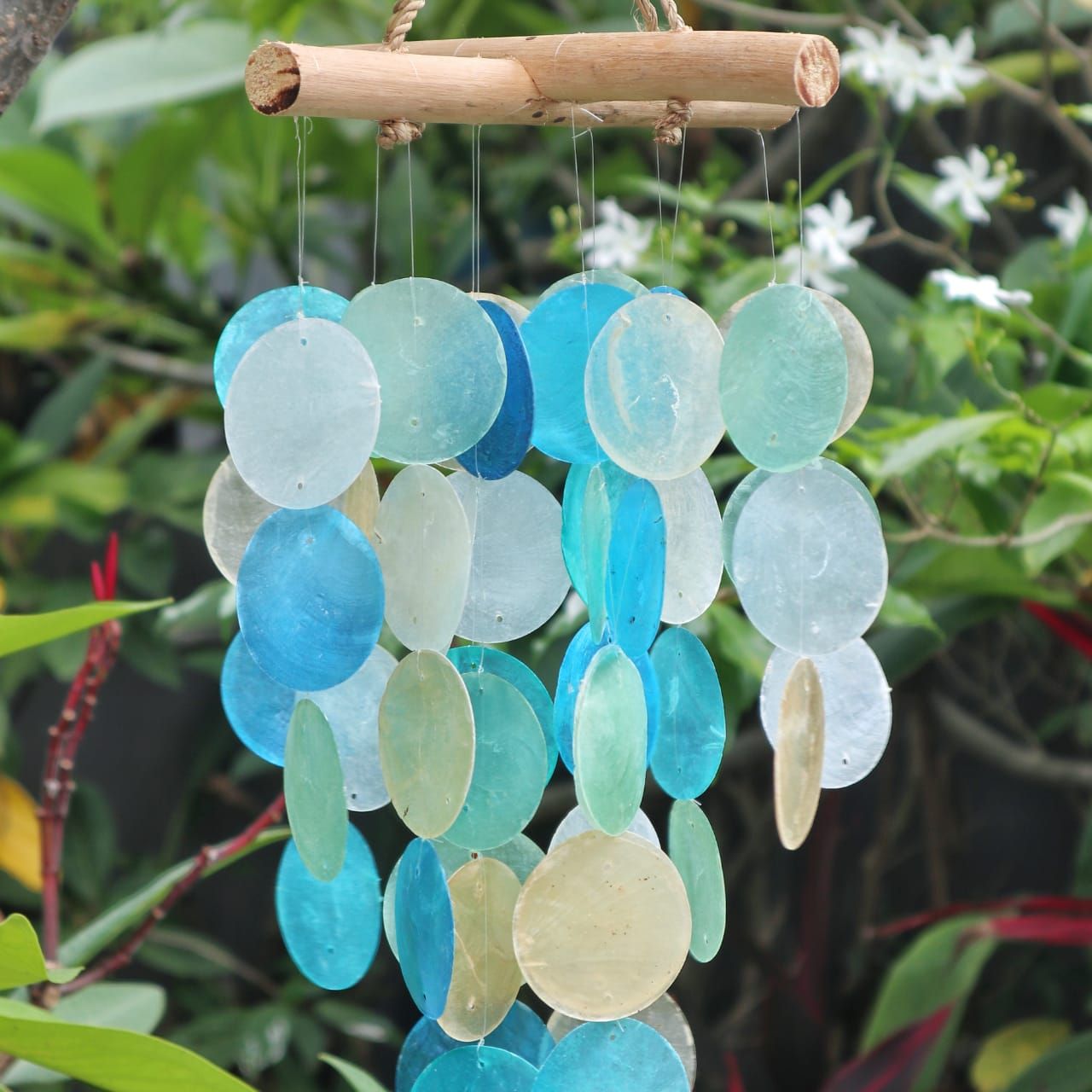 Decorative wind chime with blue and green glass beads and wooden elements against a natural background.