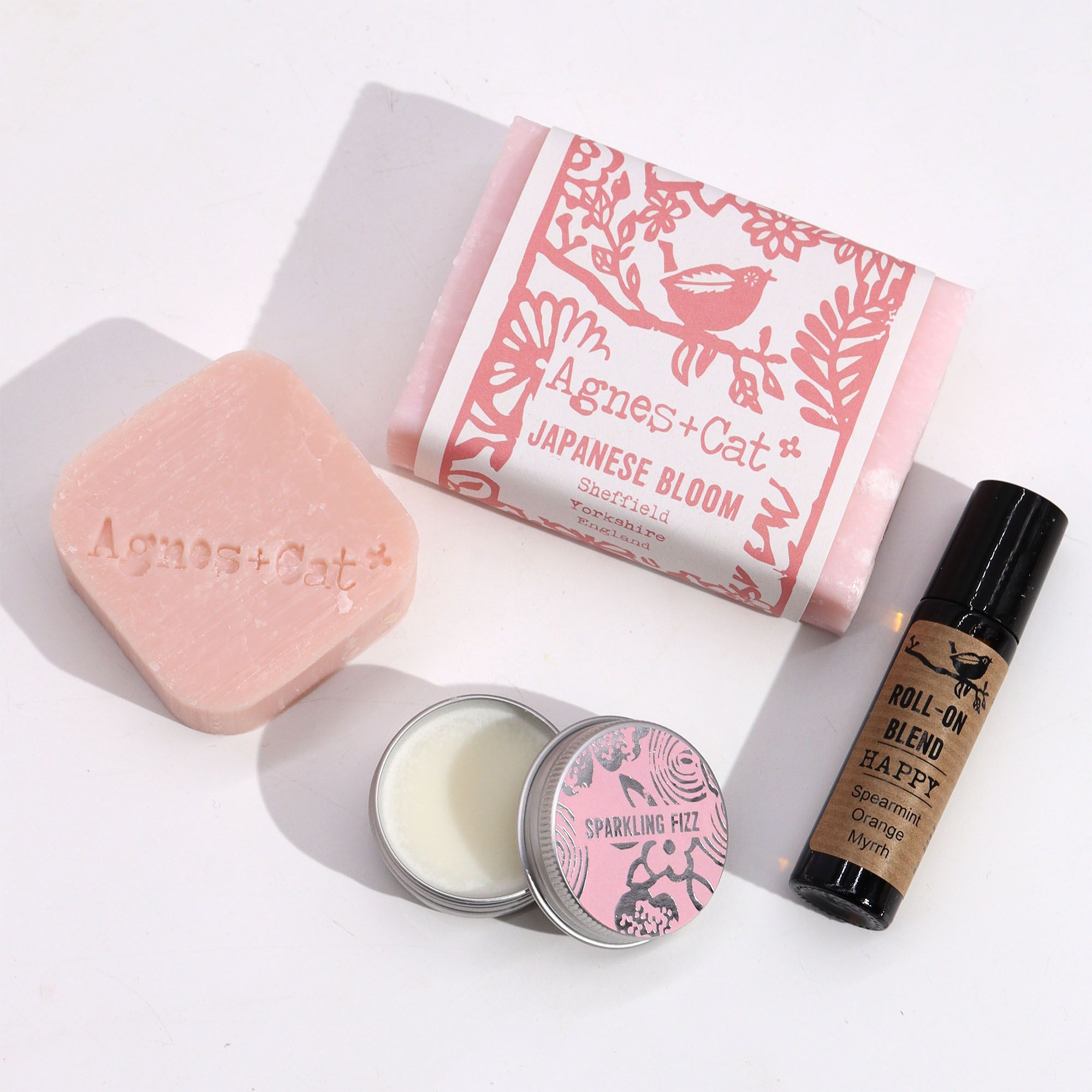 Collection of Agnes + Cat products including soap, candle, and roll-on blend on a white background