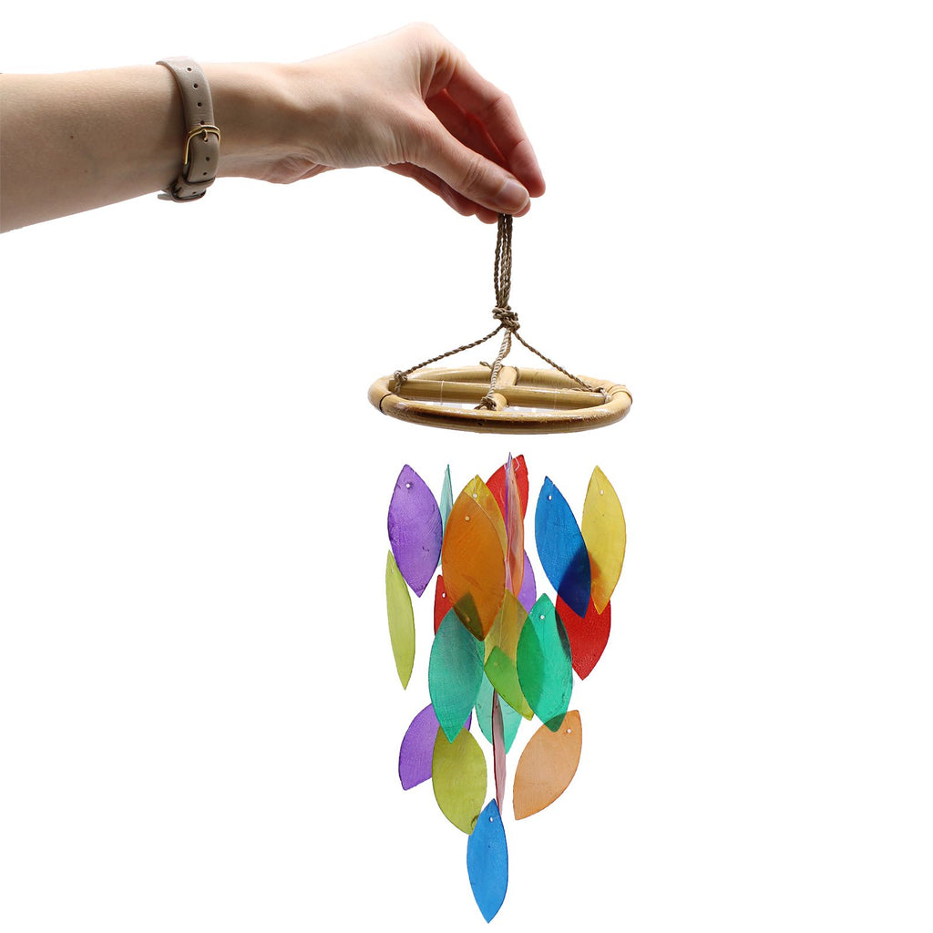 Colorful wind chime held by a hand against a white background