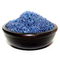 Blue sand-like material in a black bowl on a white background