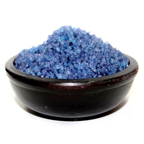 Blue sand-like material in a black bowl on a white background