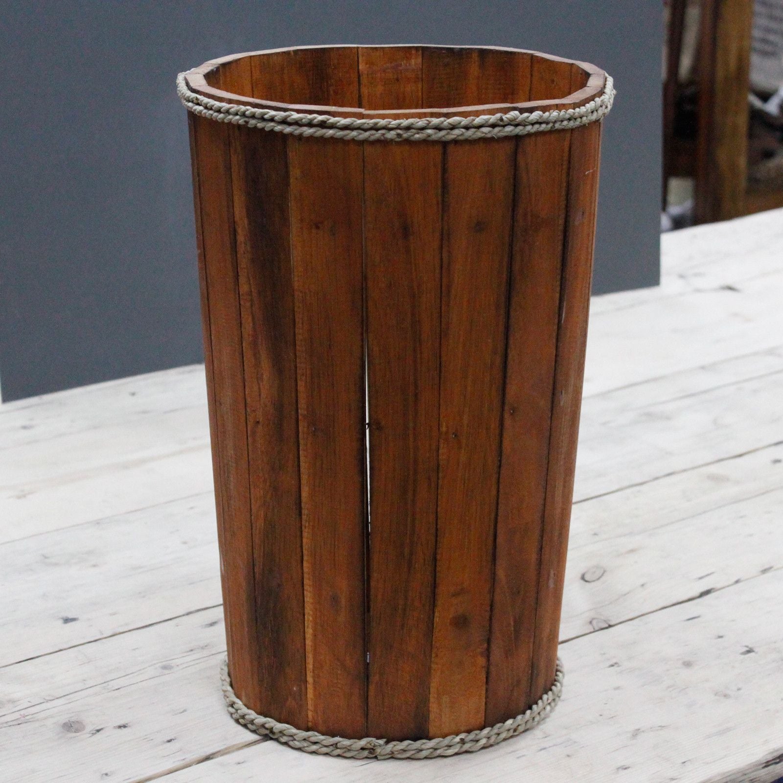 Wooden trash can with rope detailing on a wooden surface
