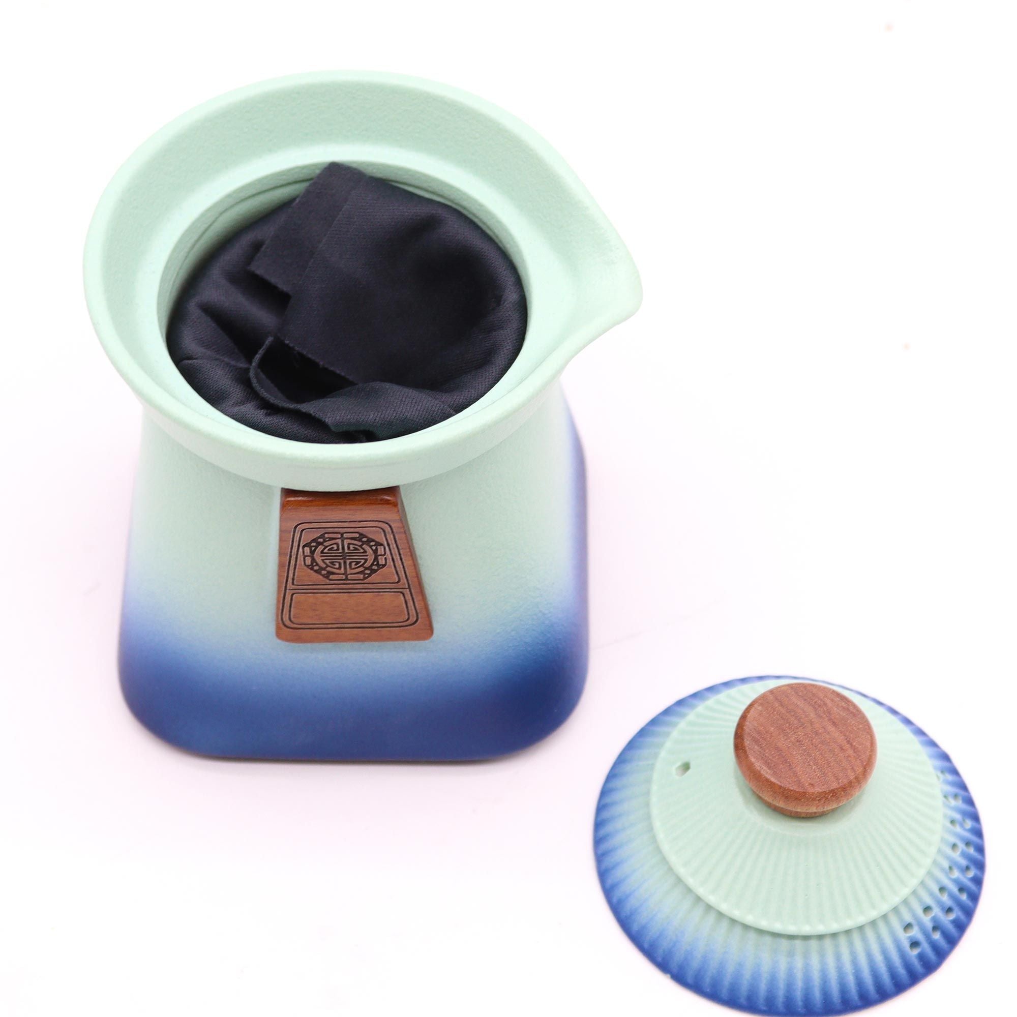 Gradient blue to green ceramic teapot with a brown lid on a white background