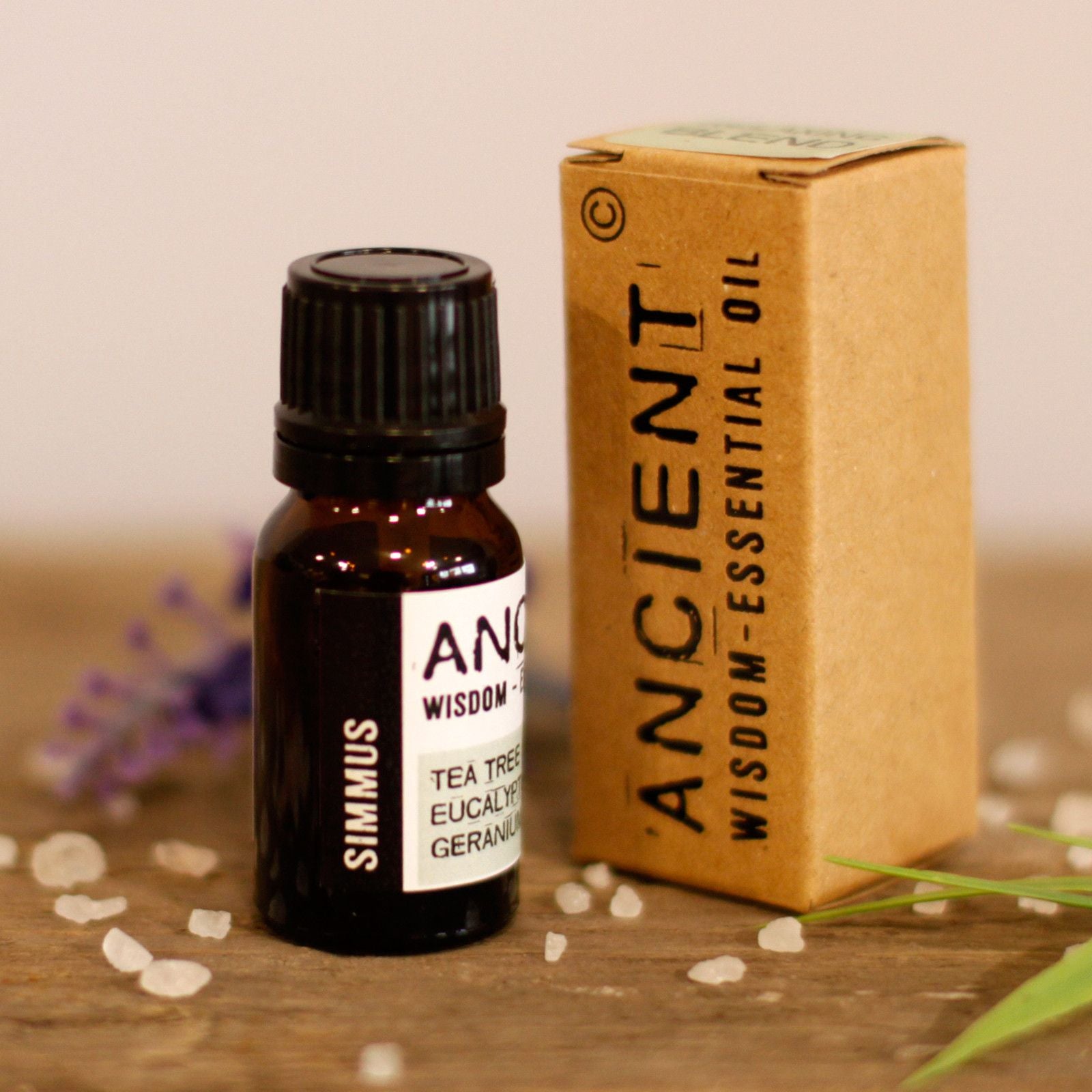 Ancient Wisdom essential oil bottle and box on a wooden surface with blurred background