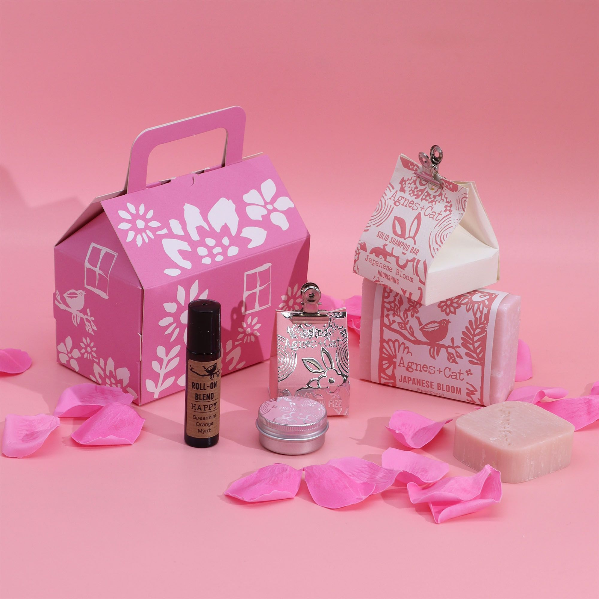 Cosmetic set with pink packaging and products on a pink background