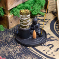 Incense burner with a Buddha statue and incense sticks on a decorative mat.