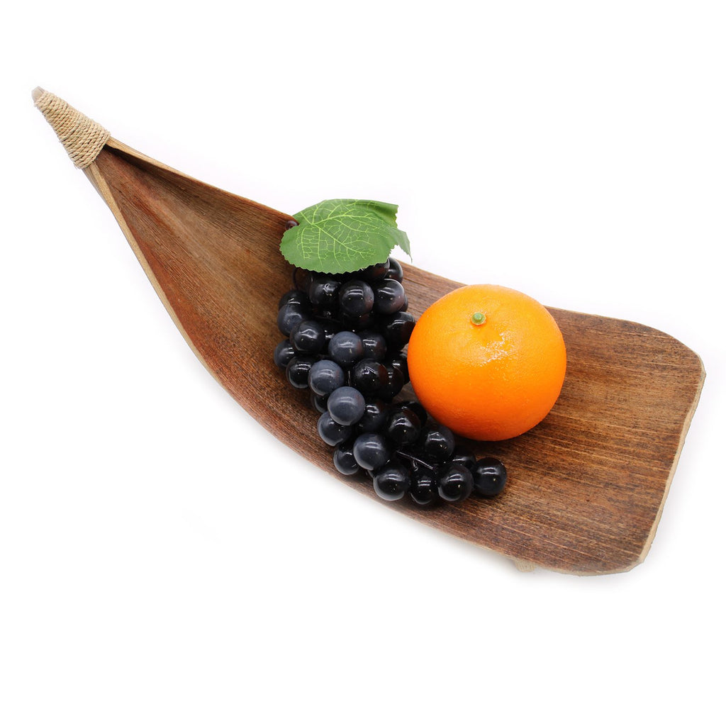 Wooden leaf-shaped platter with grapes and an orange on a white background