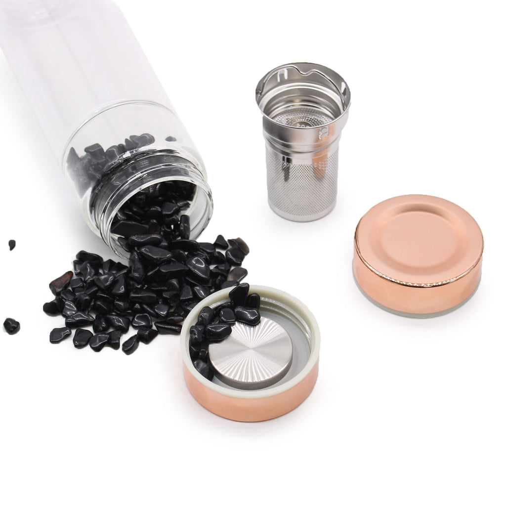 Tea packaging with black tea leaves, glass jar, metal infuser, and pink lid on a white background