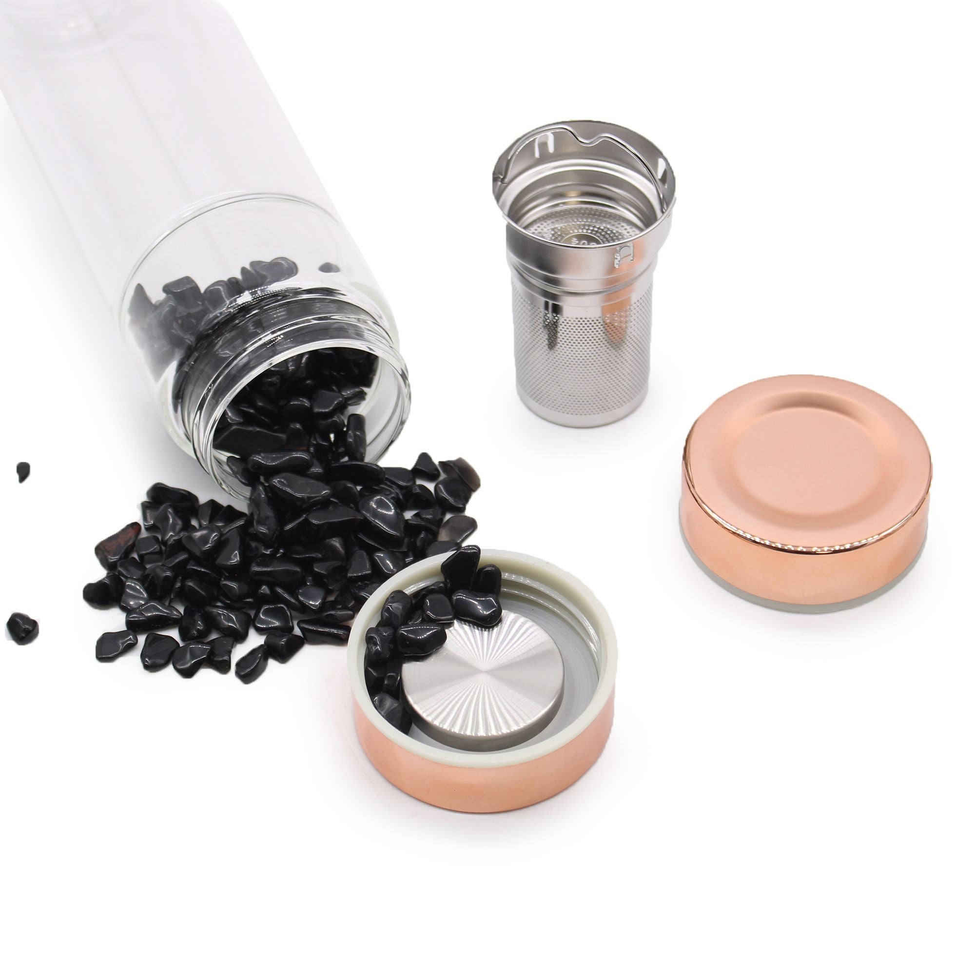 Tea packaging with black tea leaves, glass jar, metal infuser, and pink lid on a white background