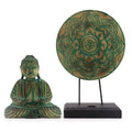 Green Buddha statue and decorative mandala on a stand against a white background